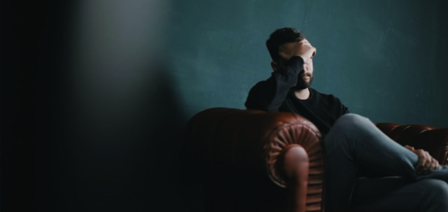 Man sitting and covering his face